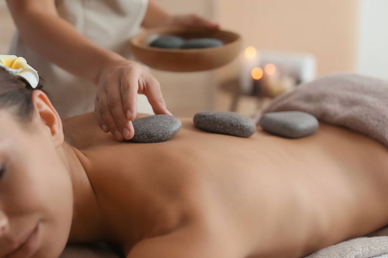 Hot Stone Massage mit erwärmten Basaltsteinen zur Entspannung und Durchblutungsförderung